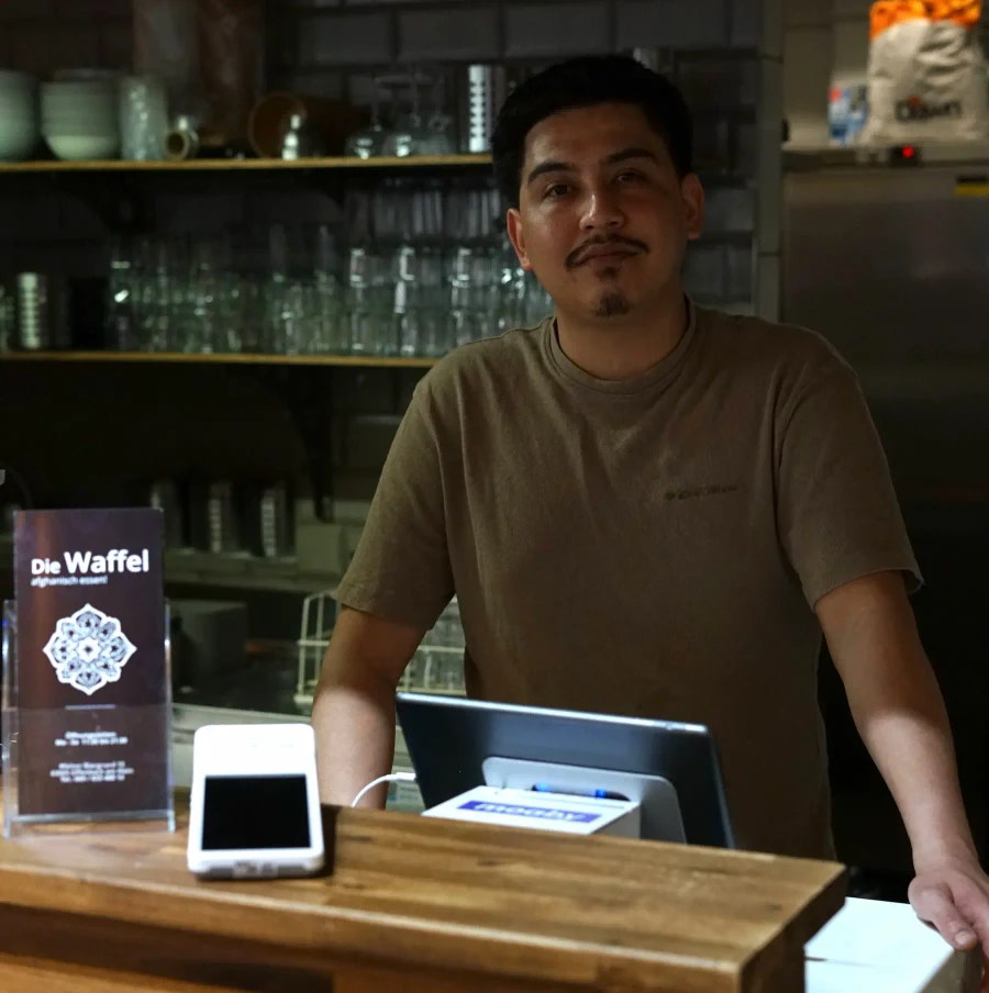 Nemad von Die Waffel hinter seiner Restauranttheke mit Kasse und Kartenterminal