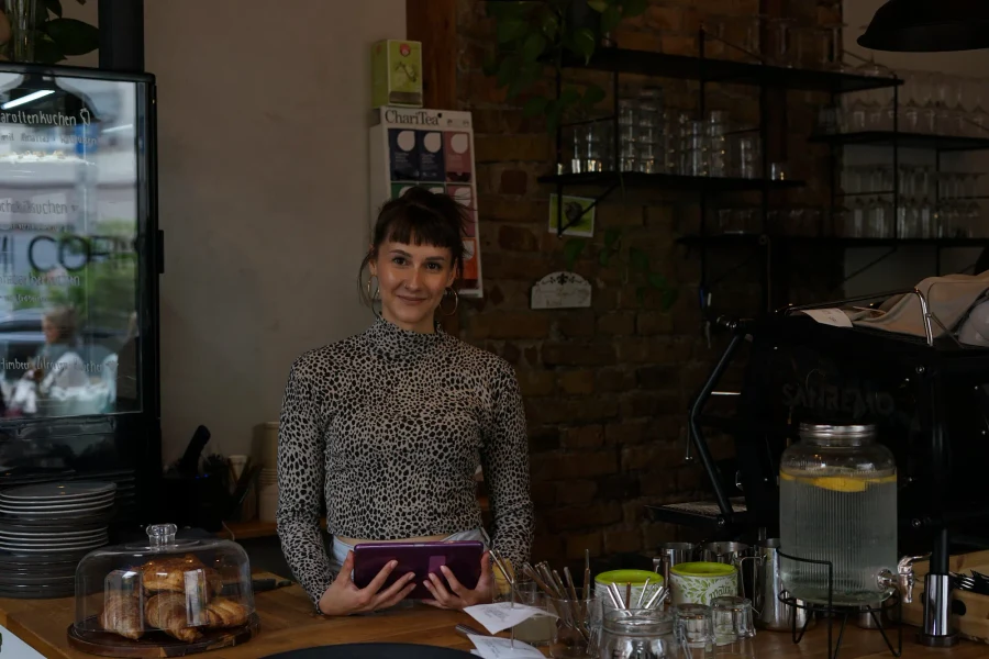 Lisa von The Kiwi Corner hinter ihrer Cafétheke mit Tablet